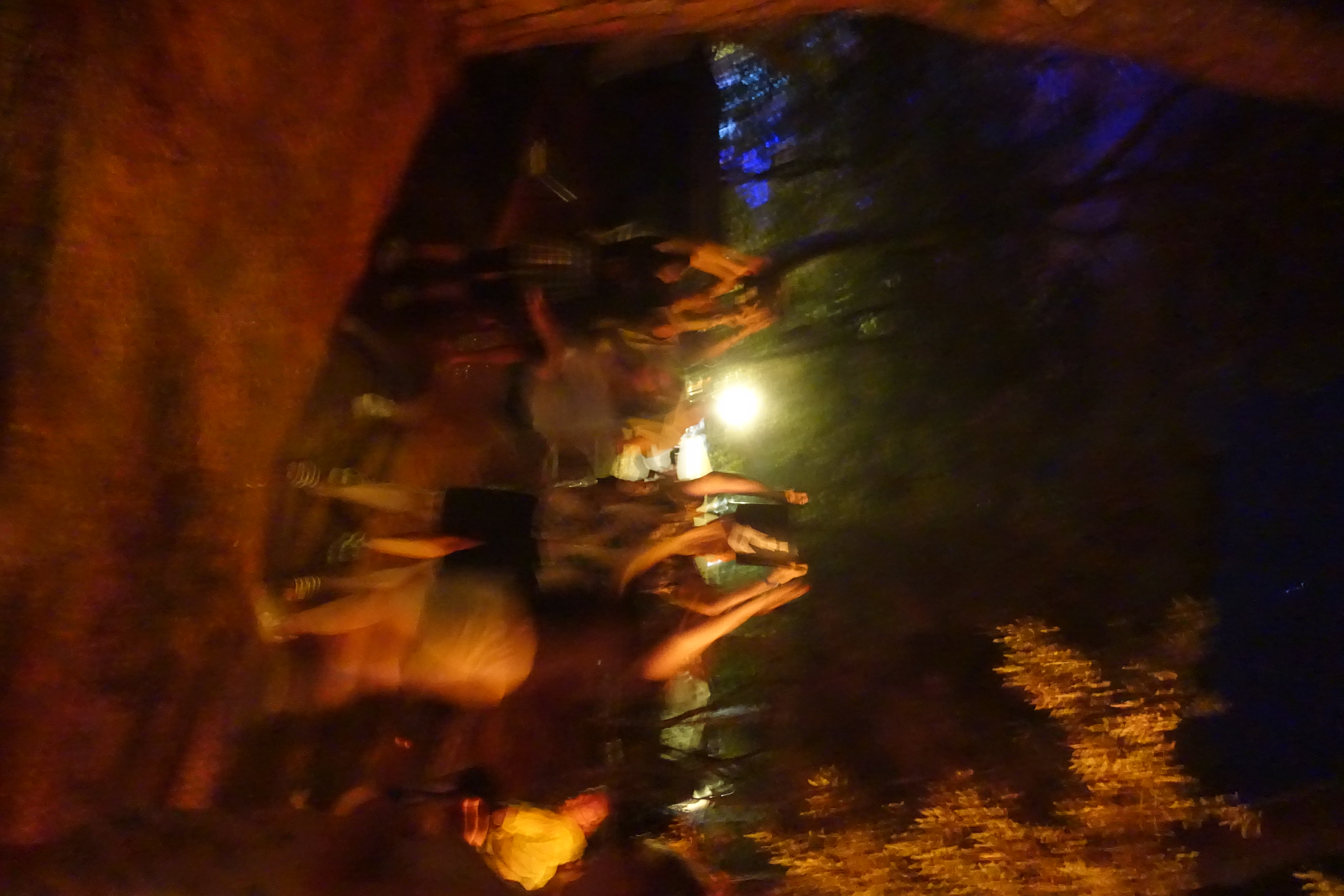 Menschen sitzen in einer großen Halle im Kerzenlicht; zwei Personen entzünden ihre Kerzen aneinander, um das Licht weiterzugeben