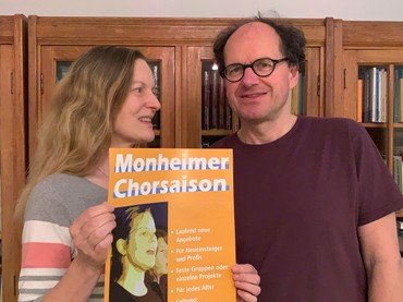 Gisela Schmelz und Matthias Standfest zeigen das Plakat zur Monheimer Chorsaison 