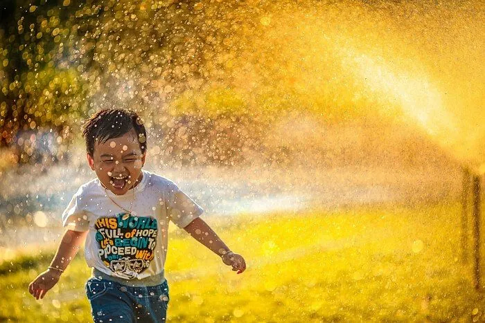 Ein Junge rennt durch eine Wasserfontäne